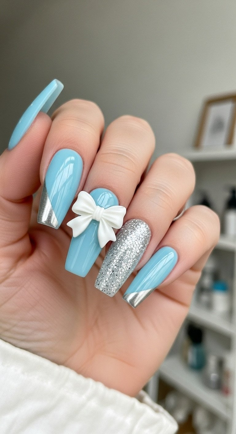 Coffin-shaped nails with reflective icy light blue polish, featuring a white 3D resin bow charm and silver glitter on accent nail. Elegant blue nail art.