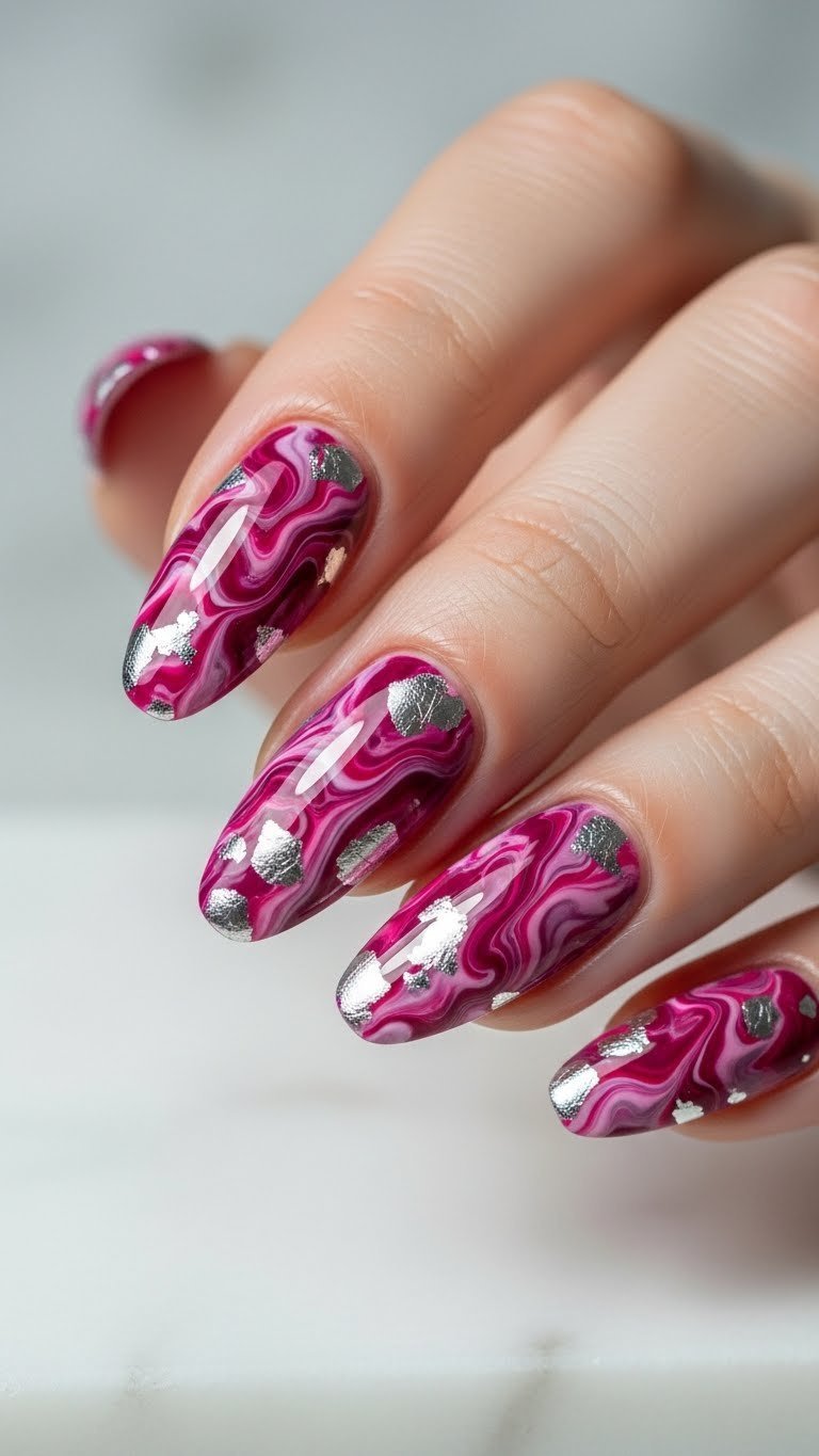 Elegant long oval nails with intricate magenta, pink, silver marbled design & foil flakes on white marble. High-end nail art.