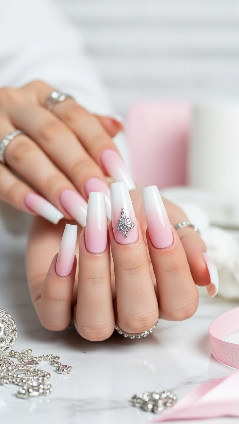 Long coffin acrylic nails with a flawless pink and white ombre, sharp apex, and C-curve, on white marble with silver jewelry.