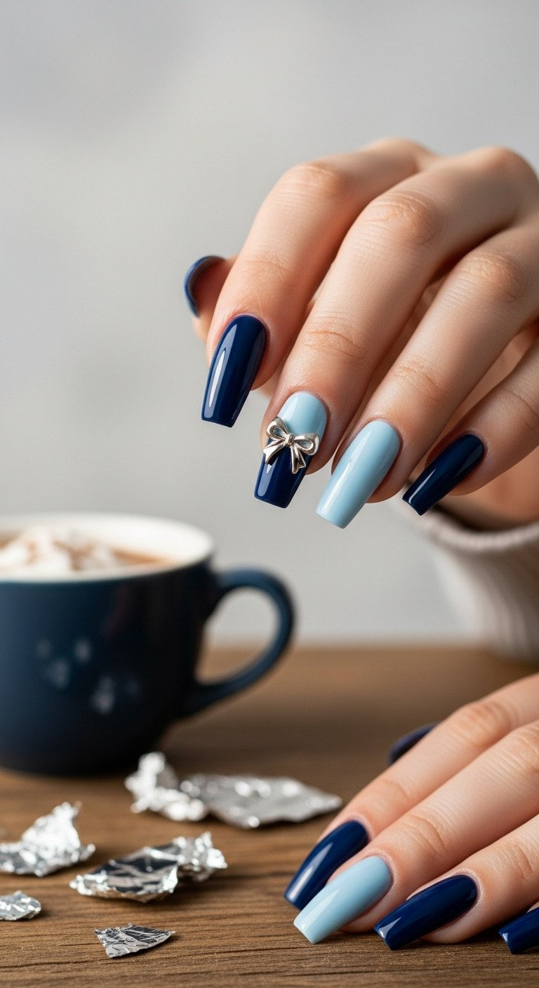 Medium nails with navy and icy blue color block design, silver metallic bow charm. Hot cocoa and foil scraps.