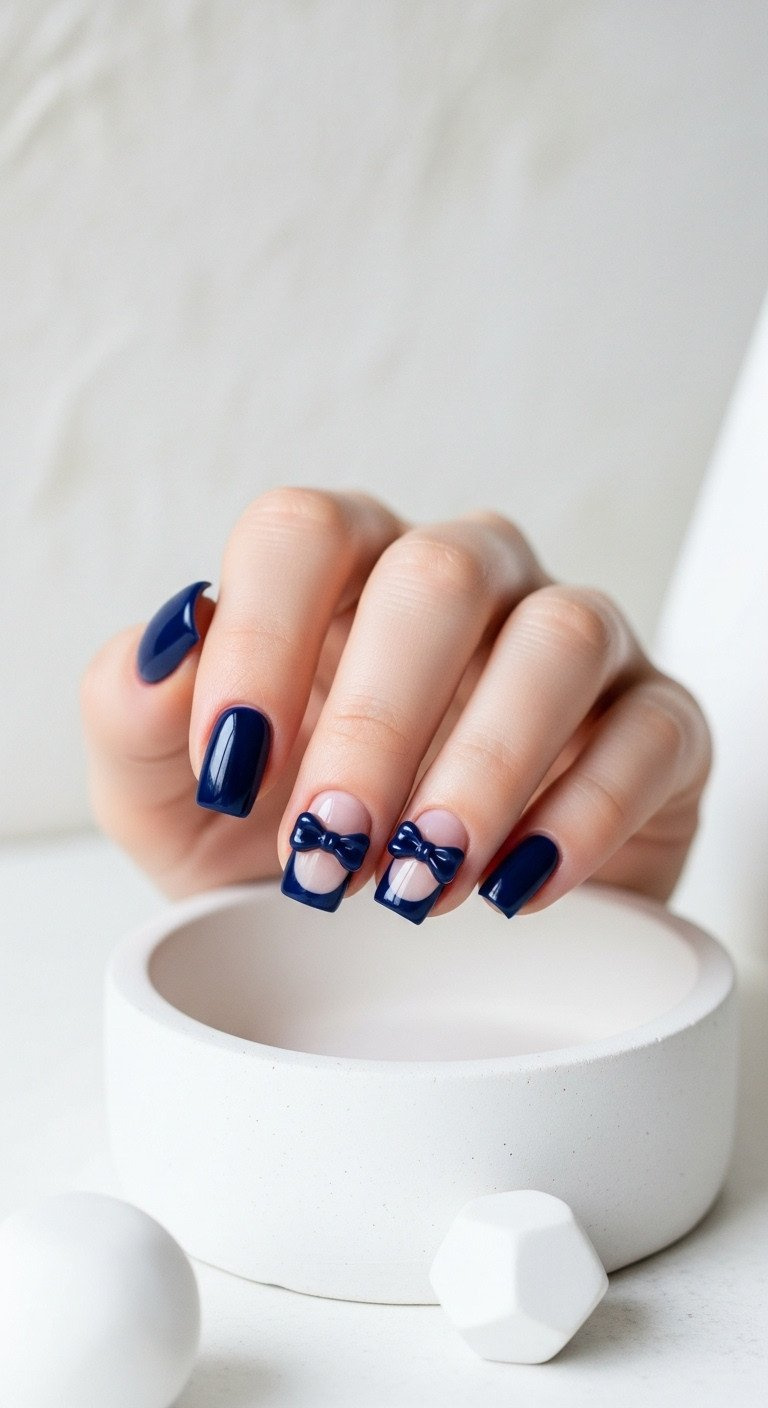 Minimalist navy blue negative space bow design on short square nails; chic, modern nail art on white ceramic.